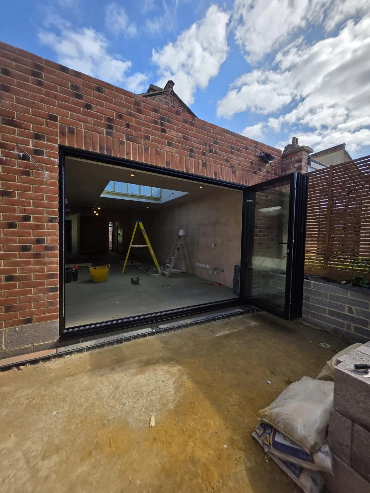 The same black aluminium bi-fold doors folded outward to the right, opening the extension to the patio