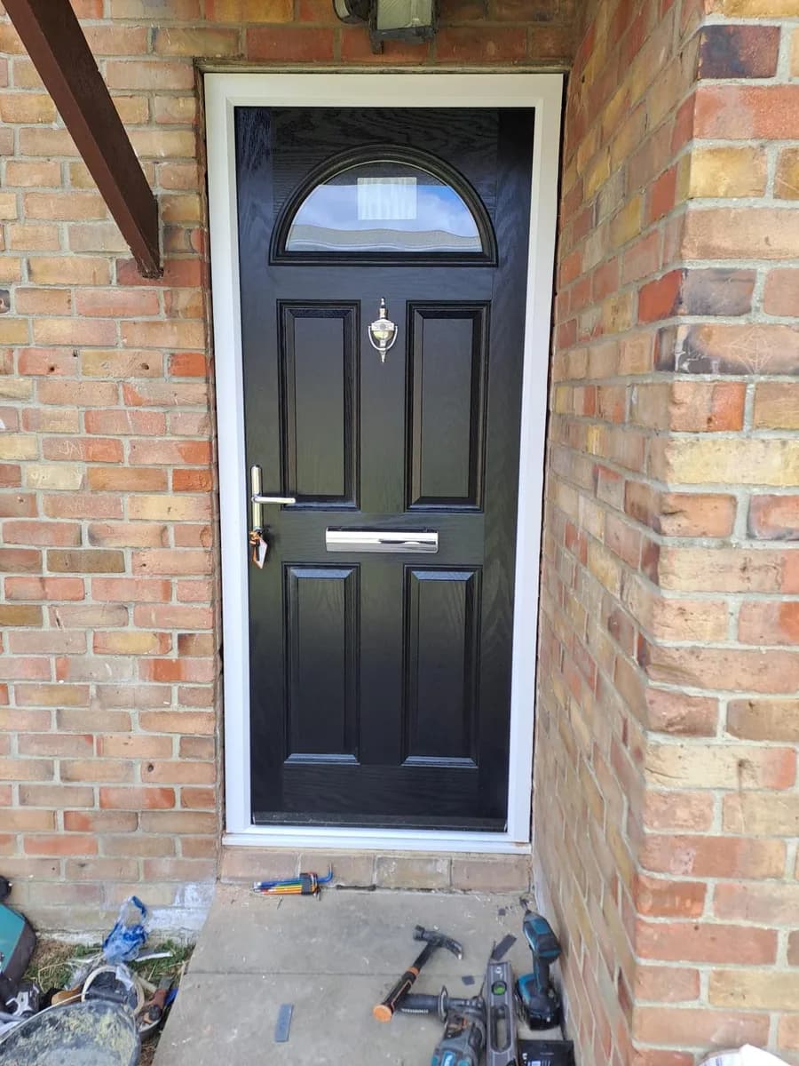 Black composite front door mid-installation in Chigwell by Cii Double Glazing, with fitting tools on the step