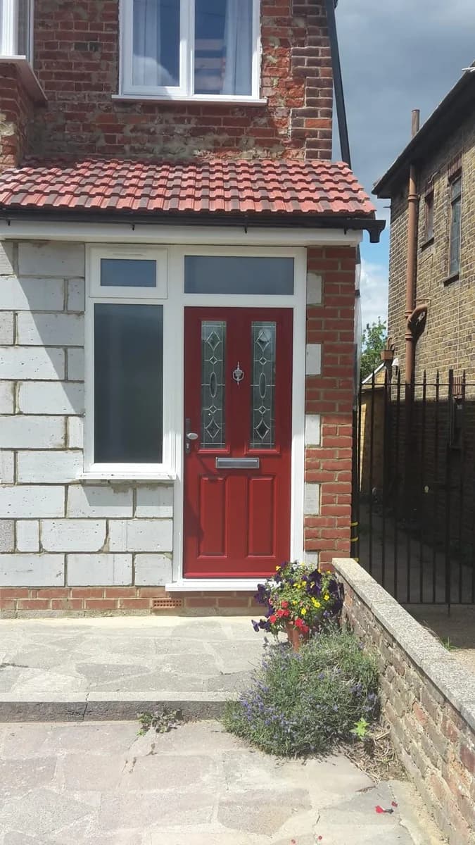 Red composite front door with a white side window and matching white frames installed in Chigwell by Cii Double Glazing