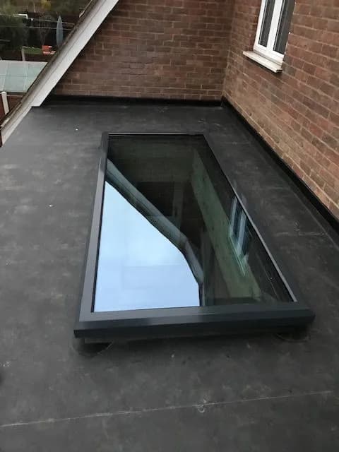 Anthracite grey aluminium flat rooflight on a raised kerb in a flat roof, installed in Chigwell by Cii Double Glazing