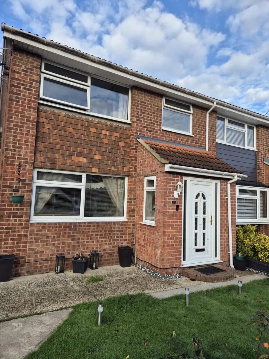 Ageing white first-floor and ground-floor windows and glazed front door before replacement on a brick house in Romford surveyed by Cii Double Glazing