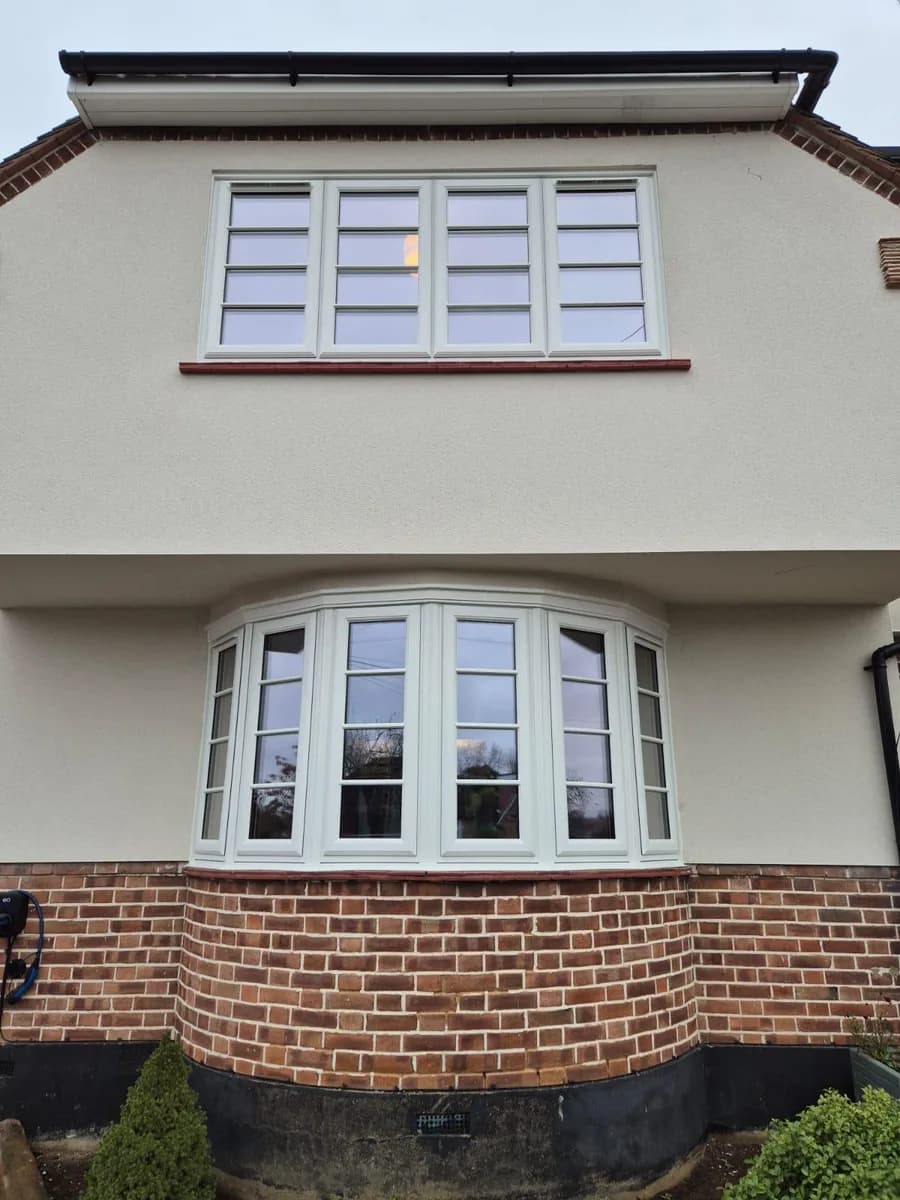 White uPVC casement windows with glazing bars in a curved bay and first-floor opening installed in Chigwell by Cii Double Glazing