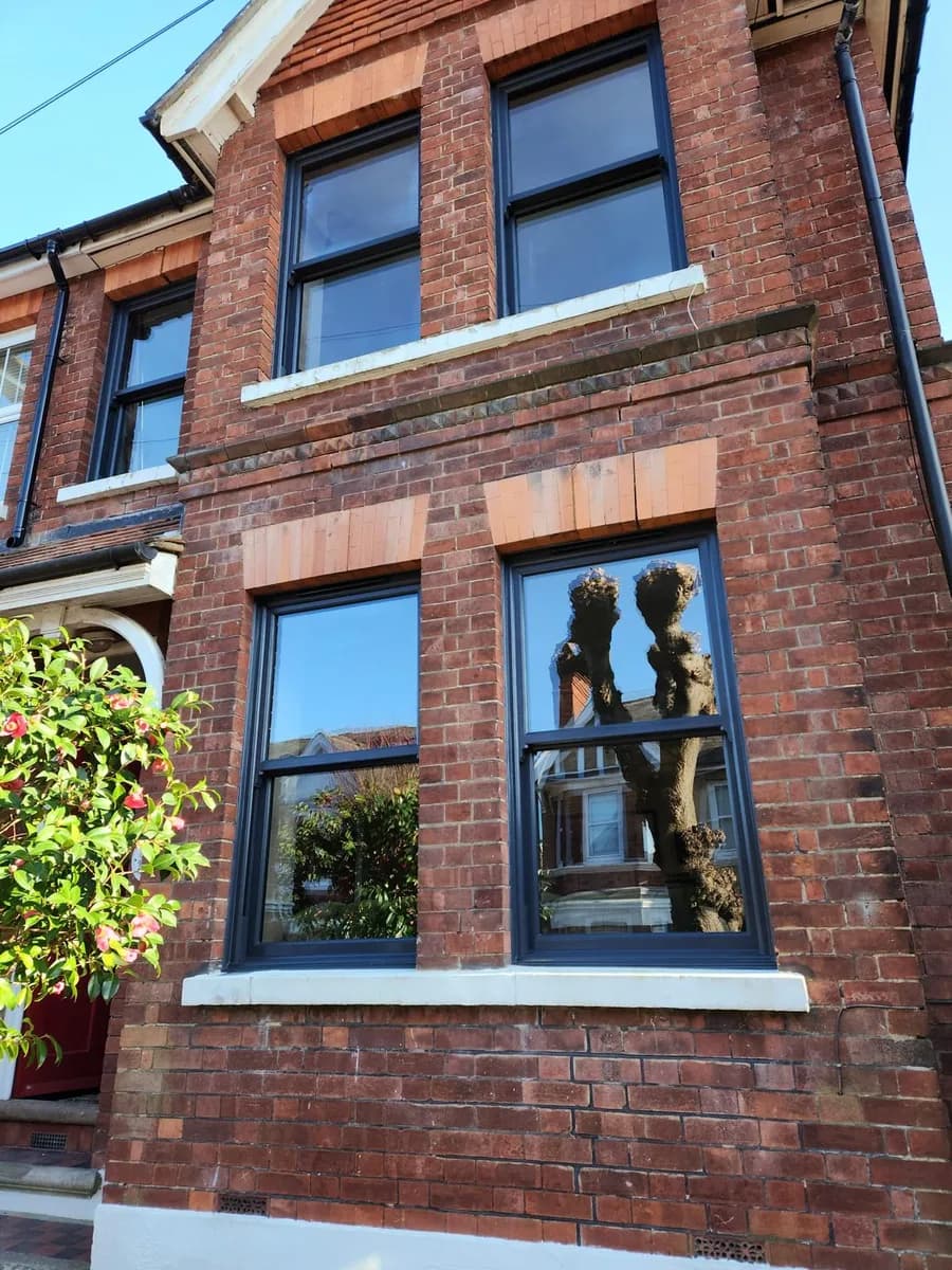 Anthracite grey uPVC sliding sash windows installed in a period brick terrace in Chigwell by Cii Double Glazing